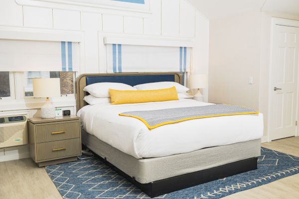 Modern bedroom with neatly made bed, nightstands, and decorative blue rug.